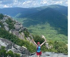 Cosette Rhoads photo. Cosette on the side of a mountain with arms out wide. 